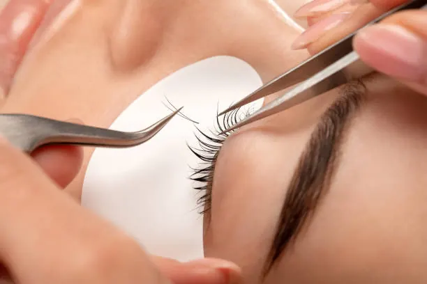 Lash extensions being applied with fine tweezers